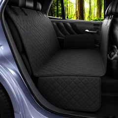 Black quilted car seat covers installed on the back seat of a vehicle, shown from the open rear door with a forest visible outside the window.
